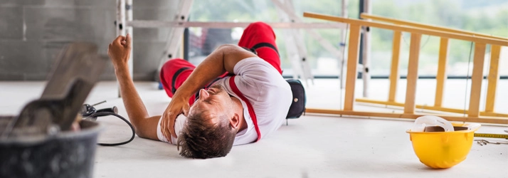 A man laying on the ground after a fall at work.